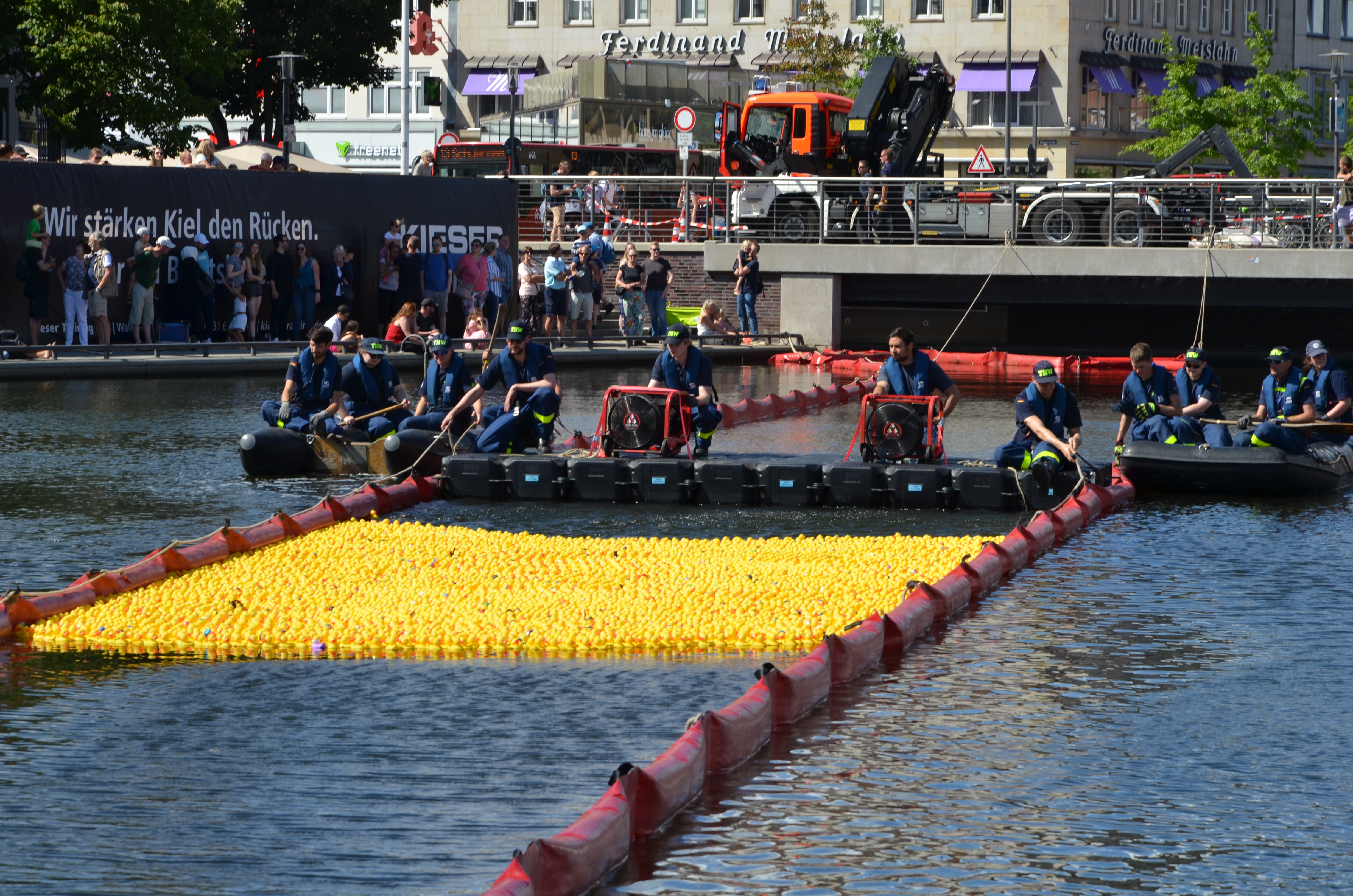 Tausende gelbe Badeenten schwimmen im Wasser und werden ins Ziel geschoben mit kleinen Gebläsen vom THW